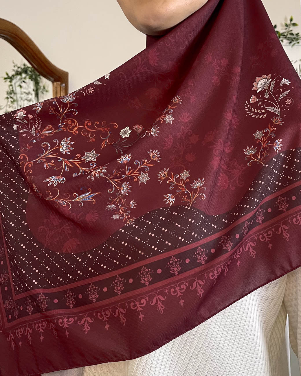 Close-up of the exquisite gold and white floral embroidery on Hadiyah's Khamrat Al Ward premium burgundy chiffon hijab fabric.
