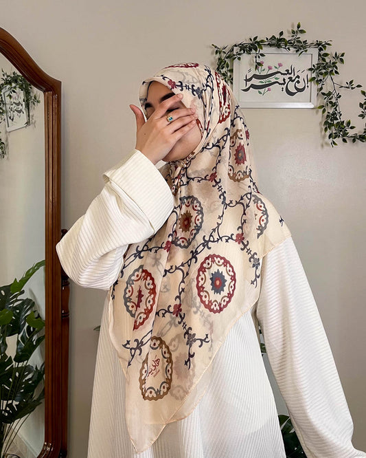 Front view of the Hadiyah Andalusia Premium Gauze Scarf, featuring intricate burgundy and navy arabesque patterns on sand beige fabric.